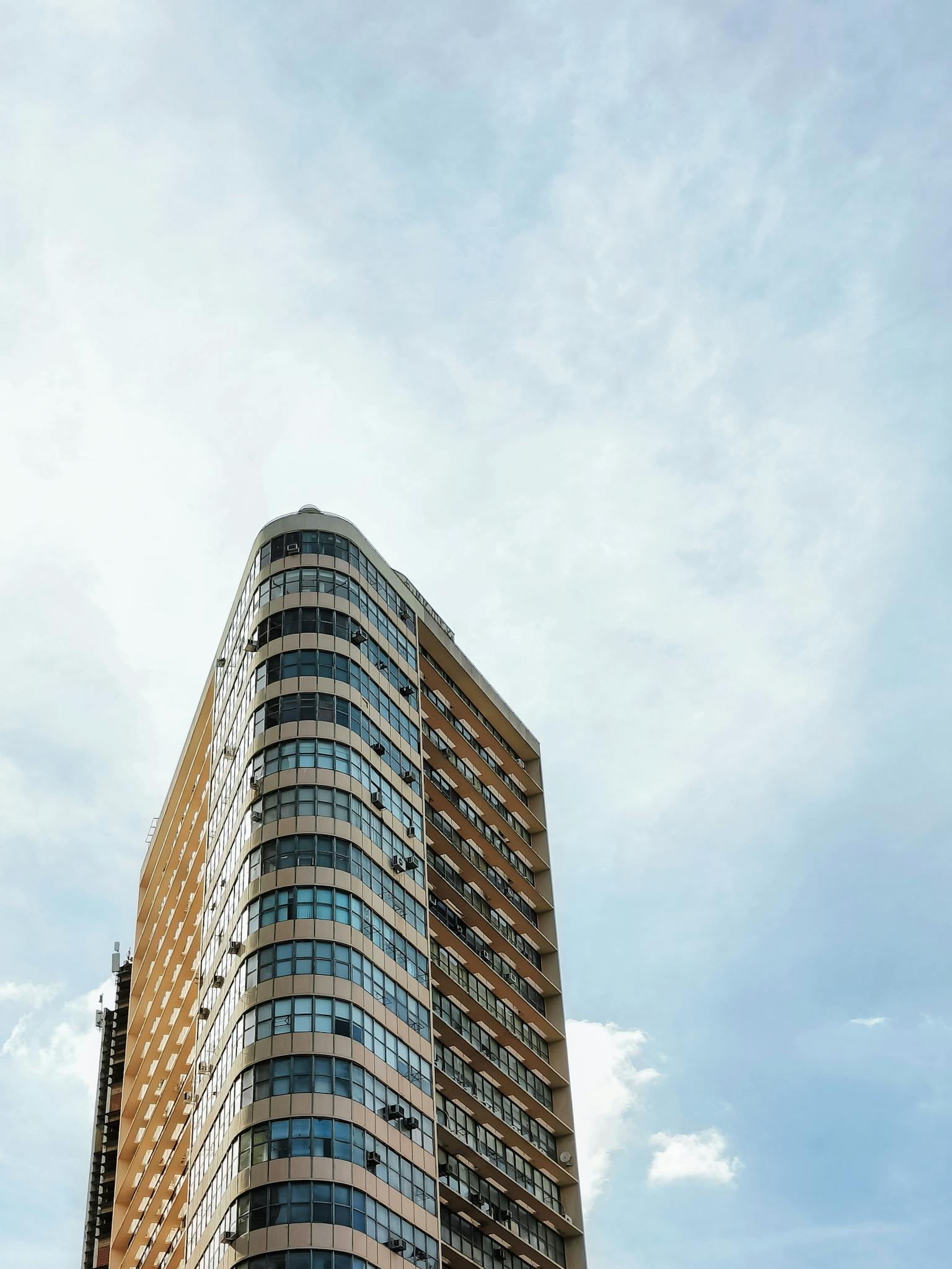 Contemporary skyscraper with curved glass facade in Belo Horizonte, Brazil, under clear blue sky.